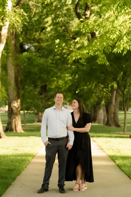 Brianna glancing up at Evan on the elm-lined walkway