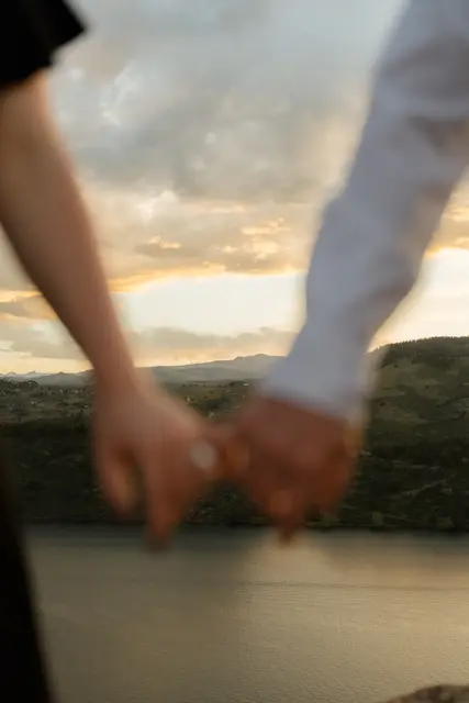 Hands laced together against the sunset sky