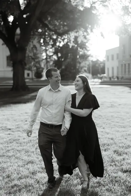 Walking arm in arm across a sunlit lawn, in black and white