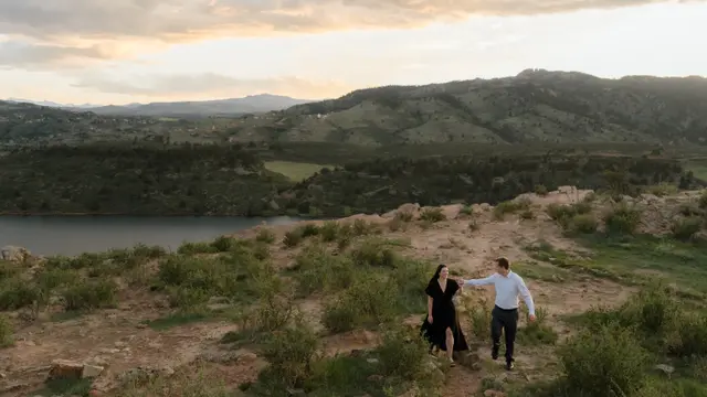 Evan leading Brianna by the hand along the ridge above the water