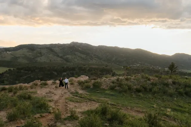 Two small figures on the ridge trail under a wide evening sky