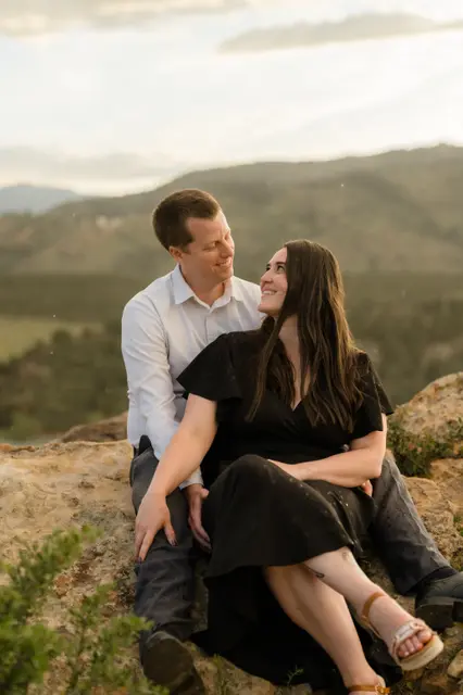 Brianna looking up at Evan while they sit on the warm rocks
