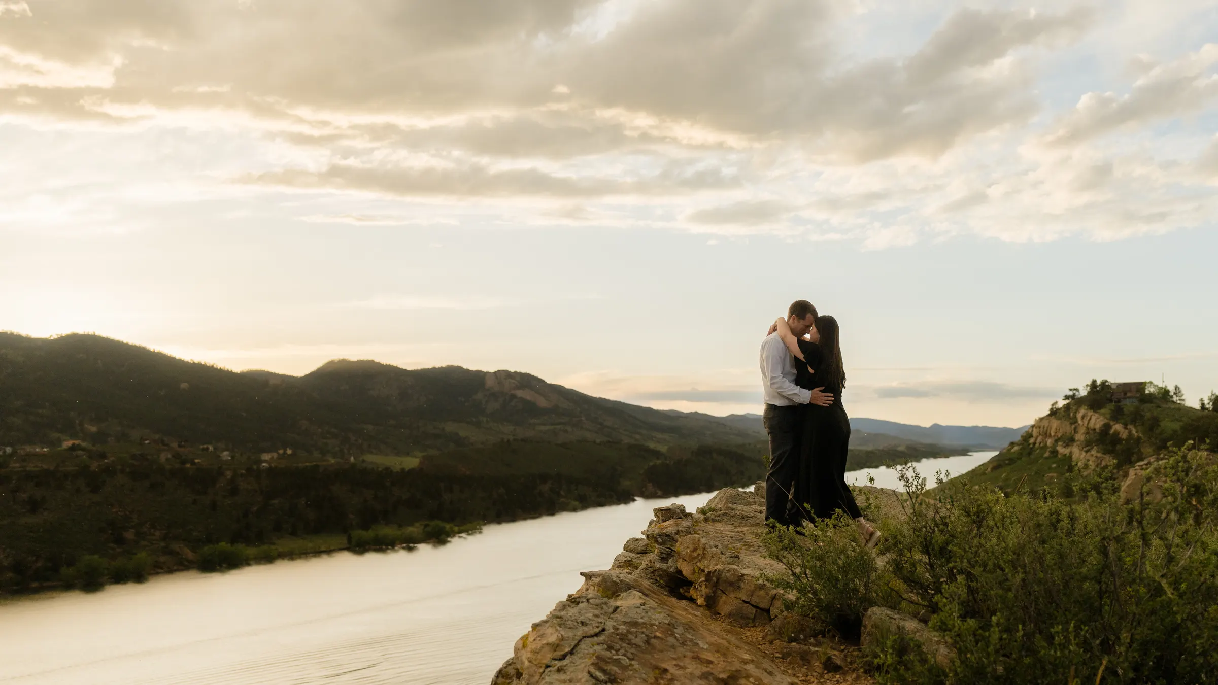 Brianna and Evan embracing at sunset on an overlook above the water