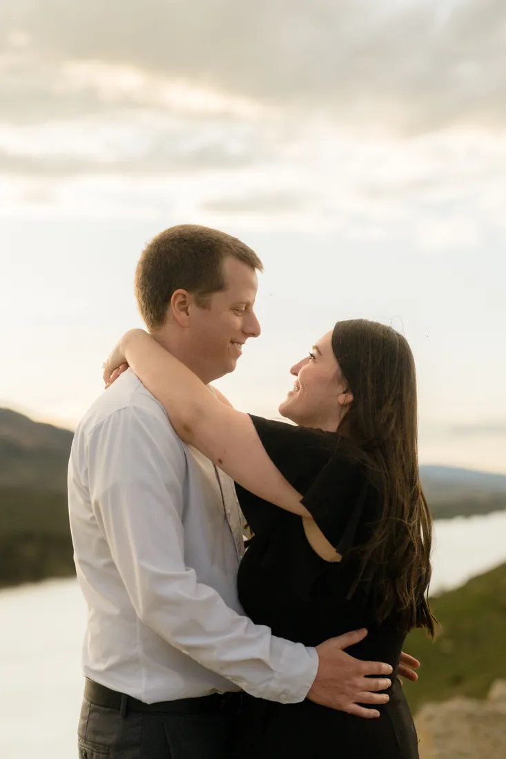Brianna looking up at Evan as they hold each other above the water at sunset