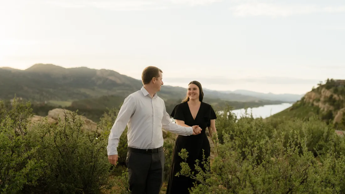 Brianna and Evan walking through high-desert brush above a reservoir